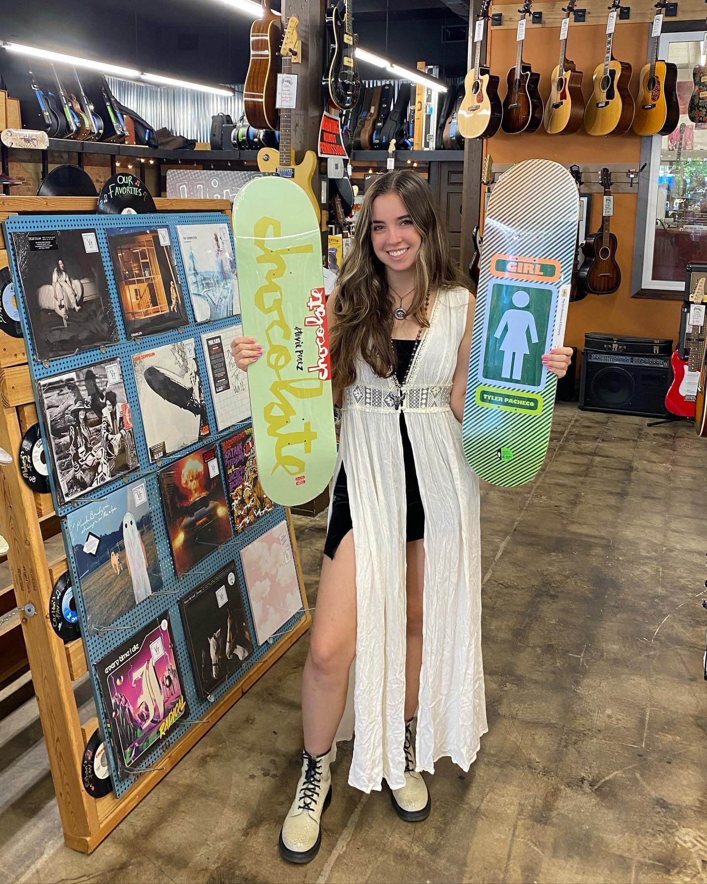 Young woman holding up two skateboard decks at Vinylyte Records & Skateshop