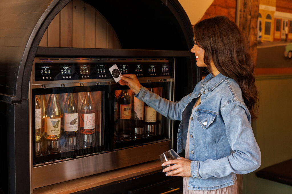 Woman using card with automated wine dispenser