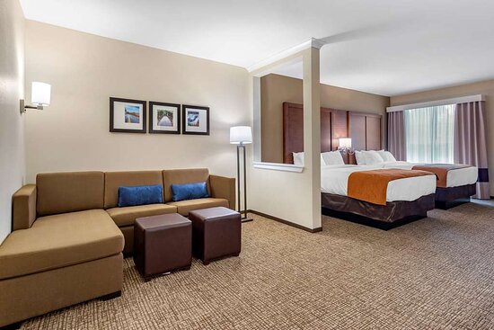 Two small beds in a suite with a full couch and TV area at Comfort Suites hotel