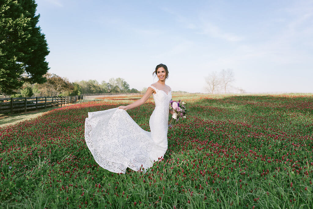 Beautiful bride posing in a field of crimson clover at The Venue at Murphy Lane