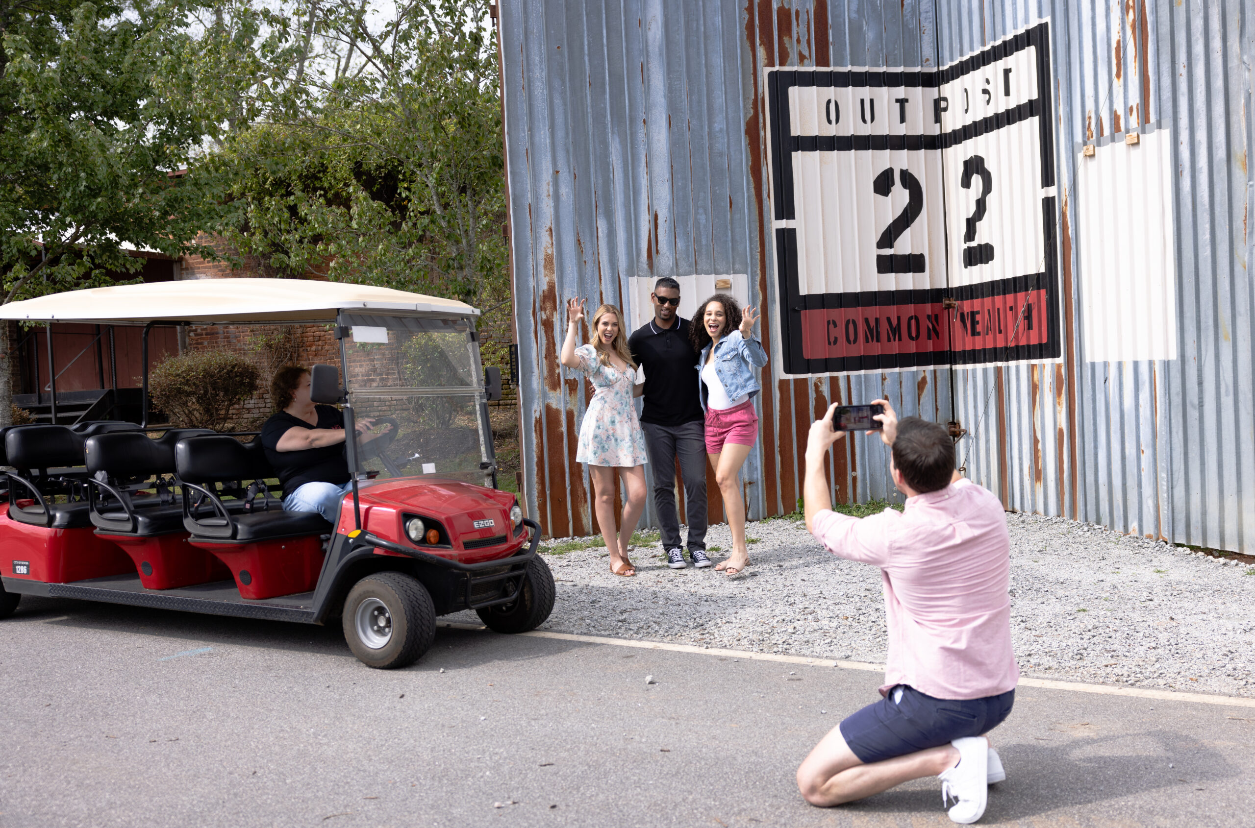 Man taking a picture of his friends next to the Outpost 22 - Common Wealth wall from The Walking Dead.