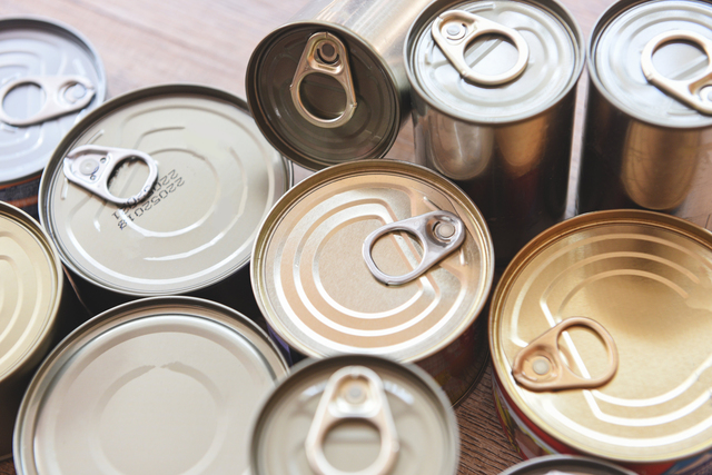 Various canned food in metal cans on wooden background