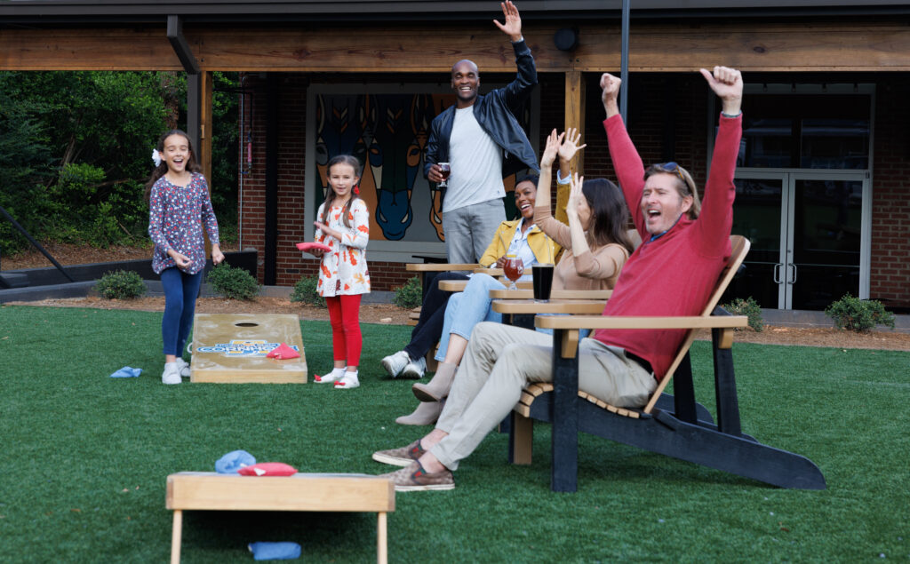 Group cheering while at a brewery and playing cornhole