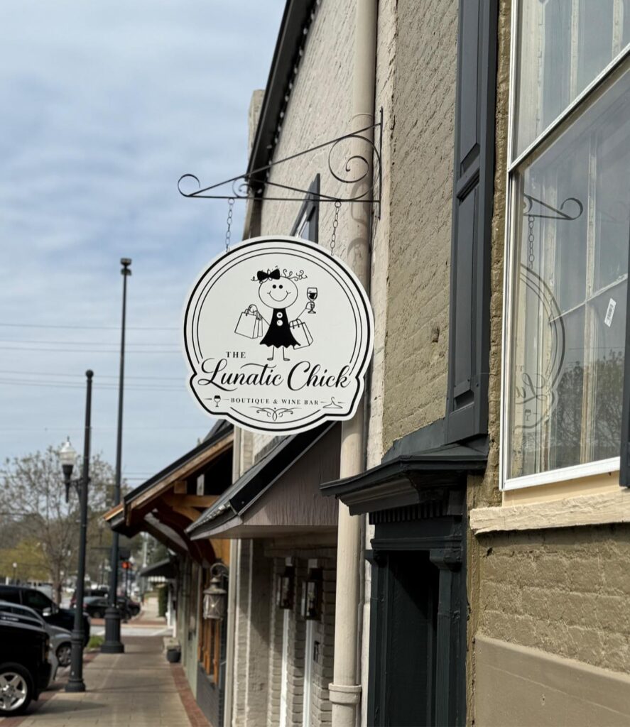 A hanging sign on the exterior of the business named 