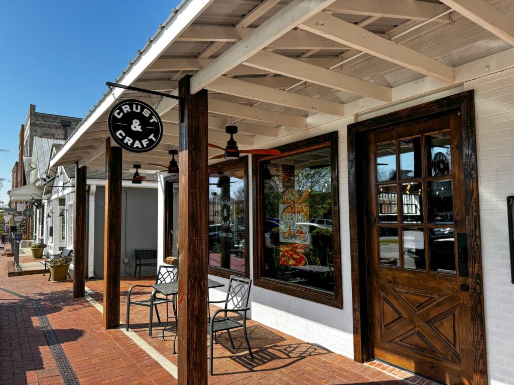 A hanging sign on the exterior of the business named 