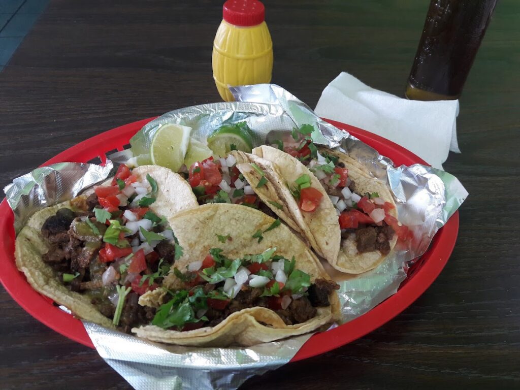 Basket of tacos with bottle of sauce on the table